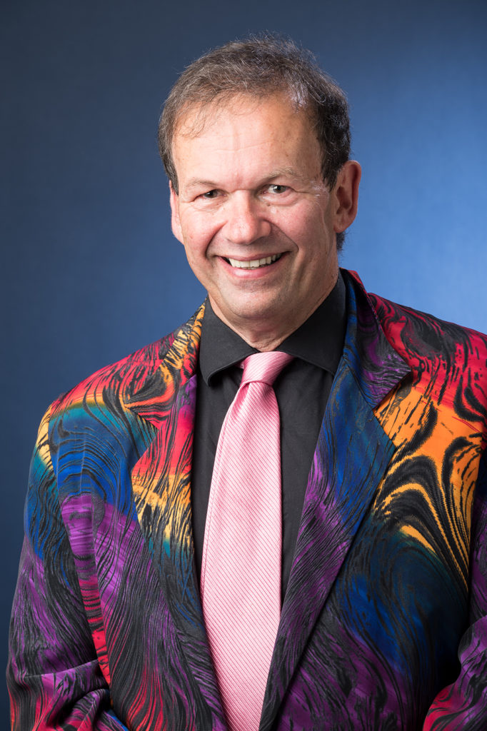 Port Phillip Mayor Cr Dick Gross wearing a multi-coloured jacket and pink tie with a contrasting black shirt.