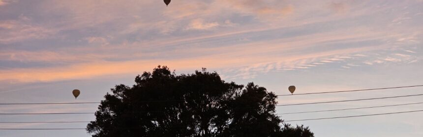 Sunrise over Bayside with pink clouds and hot air balloons